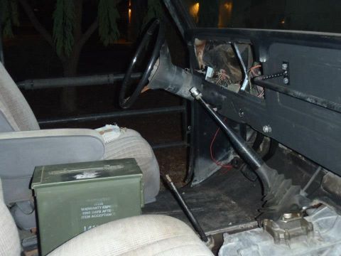 1978 Ford Bronco - The interior of a vehicle is shown, focusing on the dashboard and gear shifter area, with an ammo can on the seat.