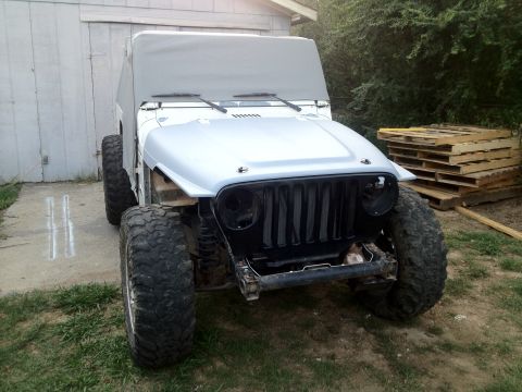 2000 Jeep TJ - Front view of a 2000 Jeep TJ undergoing body work, showing its distinctive grille and hood.