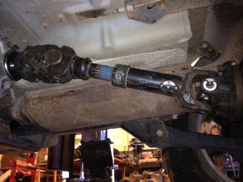 2000 Jeep Wrangler - Underside view of a vehicle's driveshaft and differential assembly, showing rusty metal parts and blue splines.