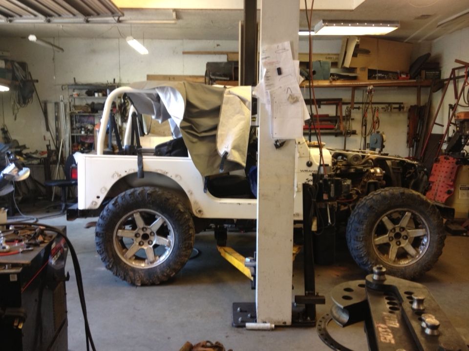 2000 Jeep TJ in a workshop, hood open, soft top partially on