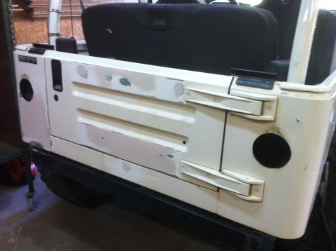 2000 Jeep TJ - The rear of a white Jeep shows signs of body repair work, including filler and primer on the tailgate.