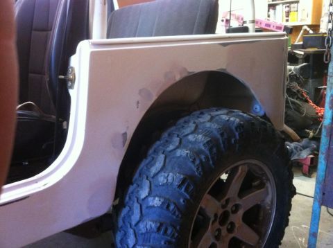 2000 Jeep TJ - The rear fender of a Jeep shows signs of bodywork and is fitted with a large off-road tire.