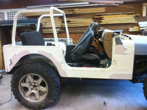 2000 Jeep TJ - Side view of a white Jeep in a workshop, showing its interior and body panels being prepared for paint.