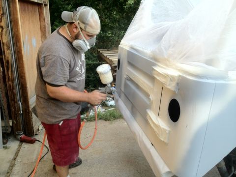 2000 Jeep TJ - Man spray painting a vehicle panel, likely during a body repair or restoration process.