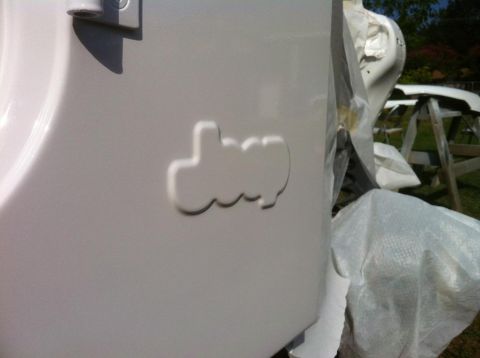 2000 Jeep TJ - Close-up of an embossed Jeep logo on a white vehicle panel, with other parts covered in protective material in the background.