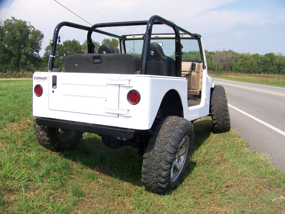 White Jeep TJ rear view with aftermarket roll cage and spare tire carrier