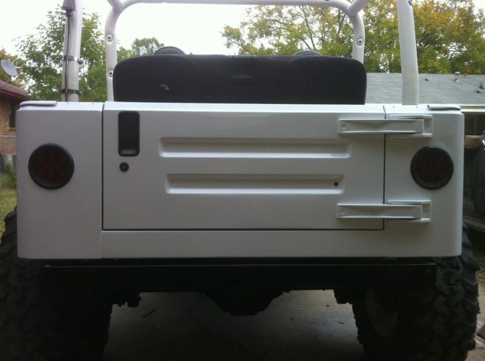 Rear view of a white Jeep with a black spare tire cover and aftermarket taillights