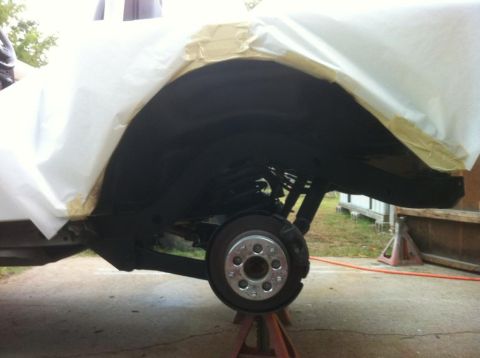 2000 Jeep TJ - Undercarriage of a vehicle undergoing maintenance, with the wheel assembly exposed and suspension components visible.