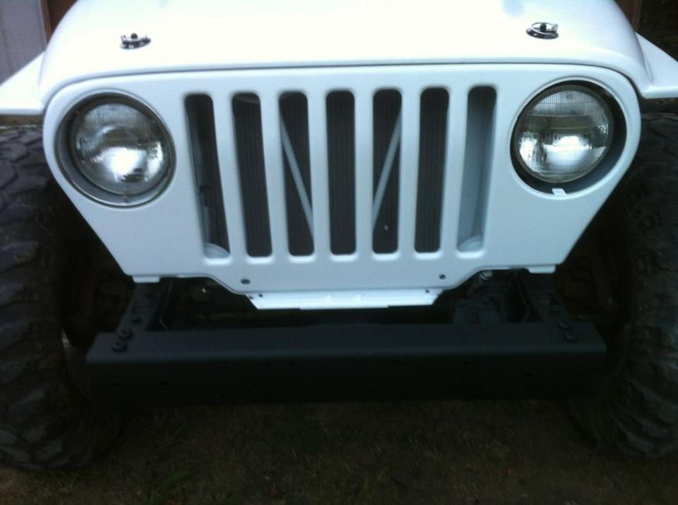 White 2000 Jeep TJ front grille with round headlights and black bumper