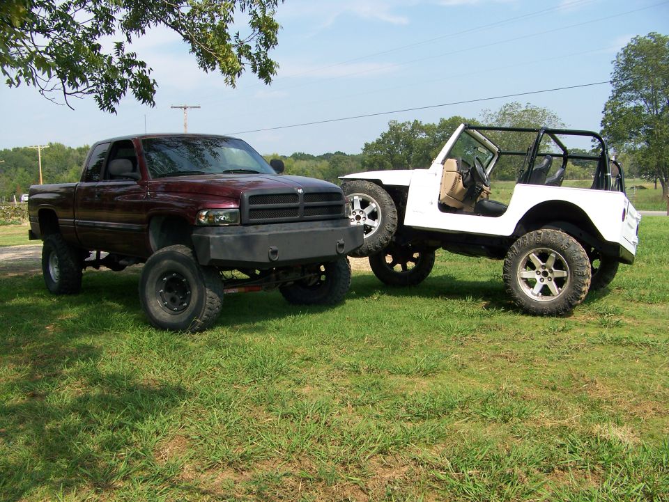 Maroon pickup truck and white Jeep parked on grass