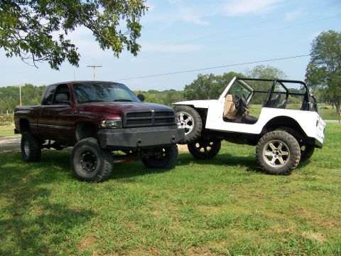 2000 Jeep Wrangler - Maroon Dodge Ram pickup and white Jeep Wrangler parked side-by-side on a grassy field.
