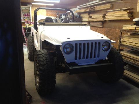 2000 Jeep TJ - This white Jeep TJ is shown in a garage, appearing to be undergoing modifications with its large off-road tires.