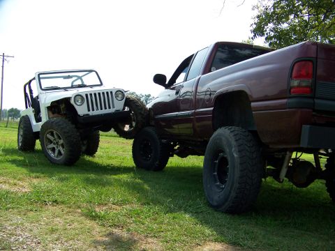 2000 Jeep Wrangler - White Jeep TJ being towed by a maroon Dodge Ram pickup truck, both lifted.