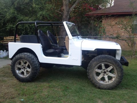 2000 Jeep TJ - This white 2000 Jeep TJ is shown with aftermarket wheels and a roll cage, suggesting modifications from its original factory appearance.
