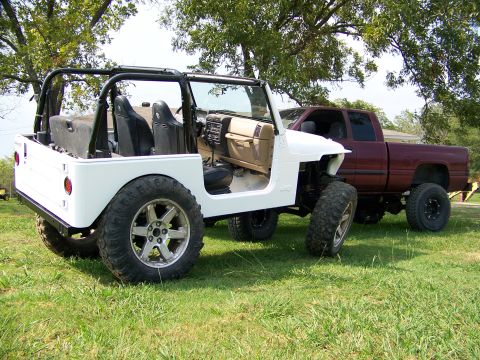 2000 Jeep Wrangler - A white Jeep Wrangler and a red pickup truck are parked on a grassy area under trees.