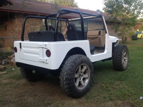 2000 Jeep TJ - This white Jeep TJ features aftermarket wheels and a roll cage, seen from a 3/4 front angle.