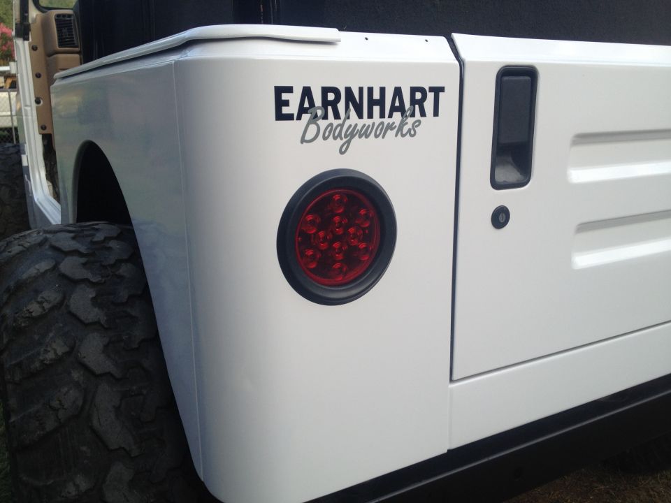 White Jeep rear quarter panel with 'EARNHART Bodyworks' decal and round taillight