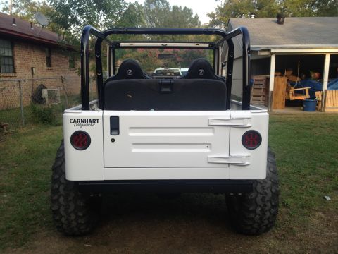 2000 Jeep TJ - This white Jeep TJ features a custom roll cage and aftermarket taillights, with a visible Earnhart Designworks decal on the rear quarter pa…