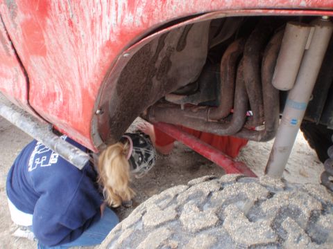 1978 Ford Bronco - A close-up view of a red vehicle's undercarriage, showing exhaust pipes and suspension components.