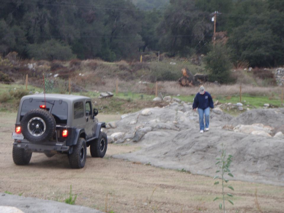 Dark gray Jeep Wrangler with spare tire on rear, seen from behind