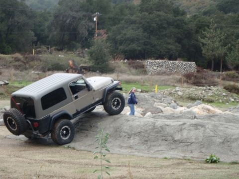 1978 Ford Bronco - A Jeep Wrangler TJ navigates an off-road obstacle course with a person observing the action.