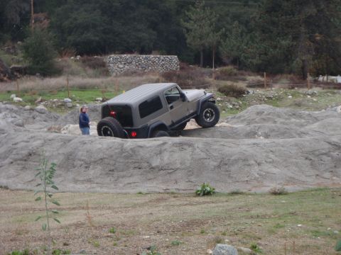 1978 Ford Bronco - A Jeep Wrangler TJ is shown maneuvering through a challenging rocky obstacle course.