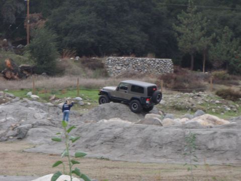 1978 Ford Bronco - A Jeep Wrangler navigates a challenging off-road course with a person observing the action.