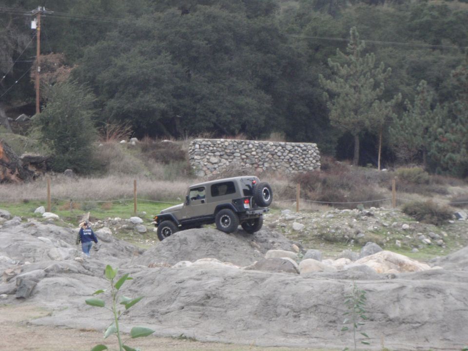 Gray Jeep Wrangler on rocky terrain, rear-mounted spare tire visible