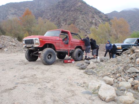 1978 Ford Bronco - A lifted red 1978 Ford Bronco is parked in a rocky, outdoor area with several people around it.