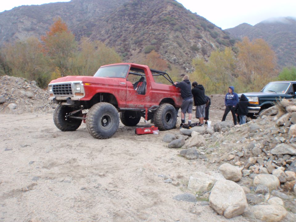 Red 1978 Ford Bronco with large tires and off-road modifications