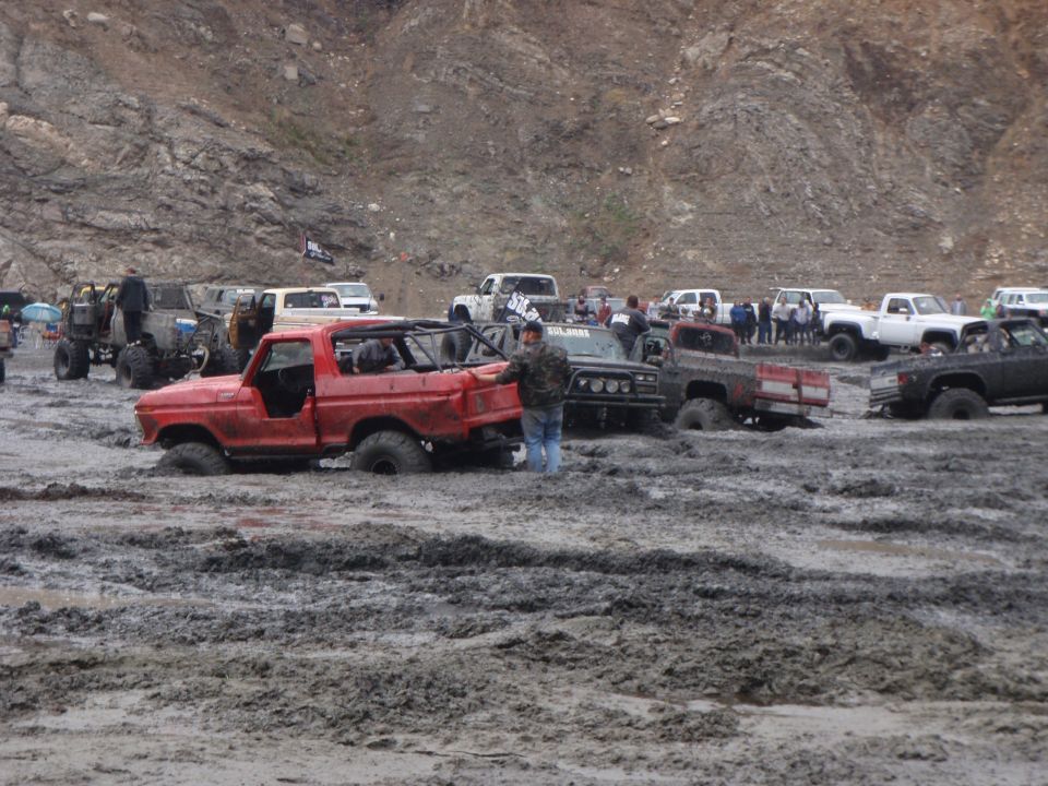Red 1978 Ford Bronco stuck in mud, 3/4 front view