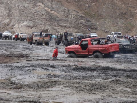 1978 Ford Bronco - Multiple off-road vehicles are stuck in a muddy terrain, with a red Ford truck partially submerged.