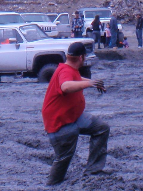 1978 Ford Bronco - A white pickup truck is stuck in the mud, with a person in a red shirt standing next to it.