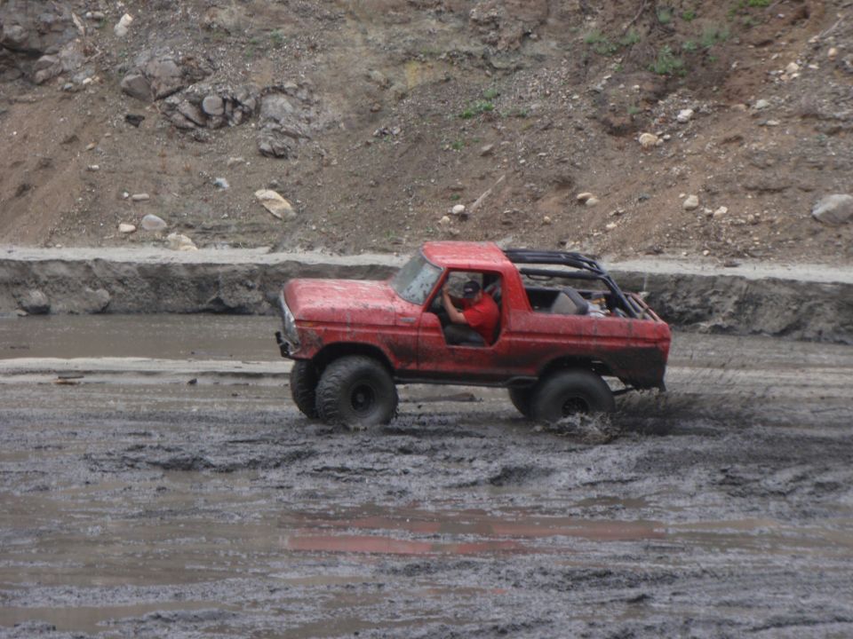 Red 1978 Ford Bronco driving through mud
