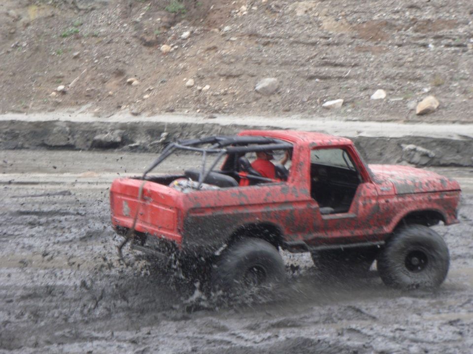 1978 Ford Bronco with roll cage driving through mud
