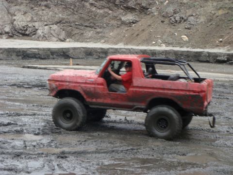 1978 Ford Bronco - A red 1978 Ford Bronco navigates a muddy off-road course.