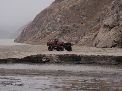 1978 Ford Bronco - Red 1978 Ford Bronco parked off-road by a lake with rocky hills in the background.