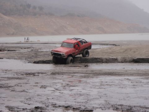 1978 Ford Bronco - Red 1978 Ford Bronco is stuck in muddy terrain near a body of water.
