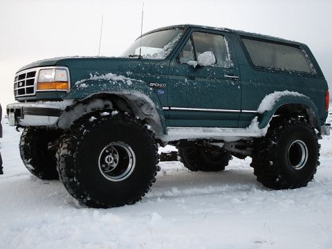 1996 Ford Bronco - Modified 1996 Ford Bronco sits in a snowy landscape with large off-road tires.