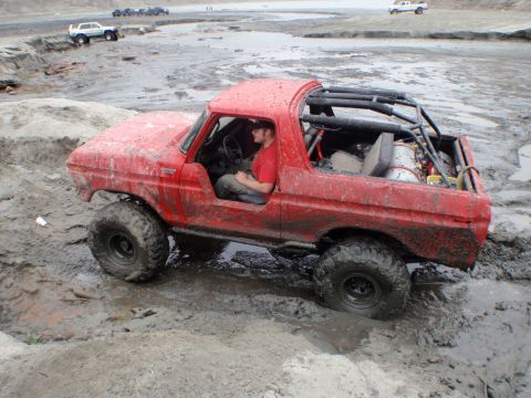 1978 Ford Bronco - This modified 1978 Ford Bronco is navigating a muddy terrain, with other vehicles visible in the background.