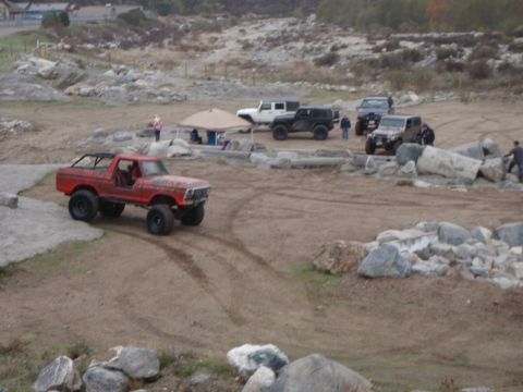 1978 Ford Bronco - A red 1978 Ford Bronco is seen navigating a rocky off-road course with other vehicles in the background.