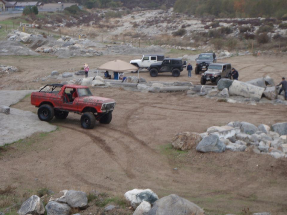 Red 1978 Ford Bronco off-road SUV with roll cage on dirt terrain