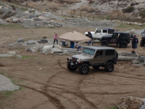 1978 Ford Bronco - Several off-road vehicles are gathered at an outdoor event, with a tan Jeep Wrangler prominently featured in the foreground.
