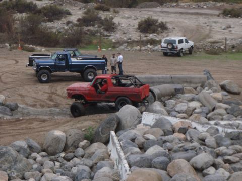 1978 Ford Bronco - Several off-road vehicles navigate a rocky terrain with a concrete barrier.