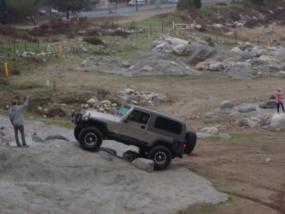 Tan Jeep Wrangler navigating rocky terrain