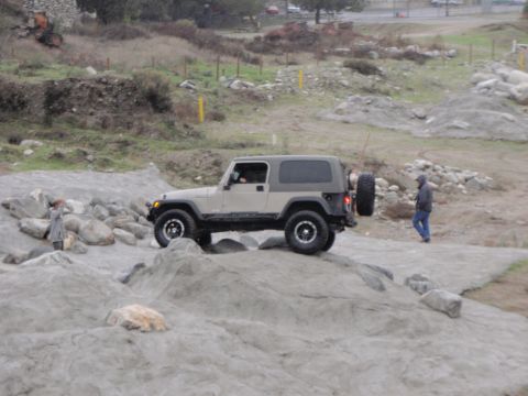 1978 Ford Bronco - A tan Jeep Wrangler TJ navigates a rocky obstacle course.