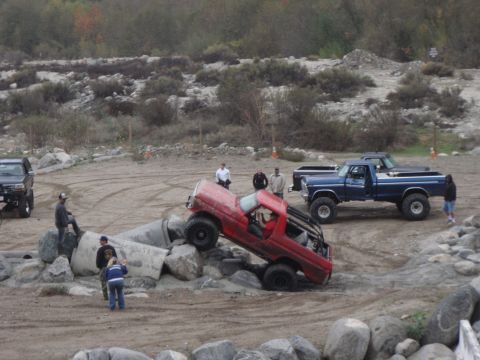 1978 Ford Bronco - Modified red pickup truck navigates a rocky terrain, with another truck waiting.