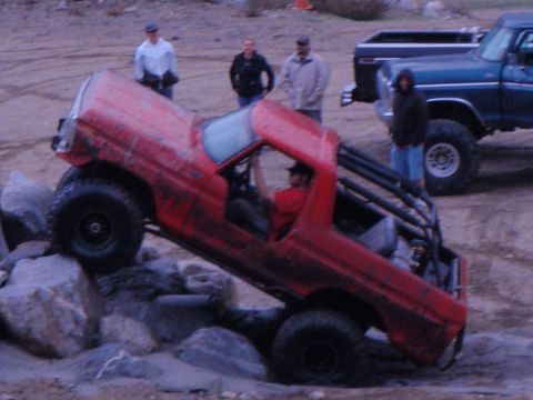 1978 Ford Bronco - A red truck navigates a rocky obstacle course with spectators watching.