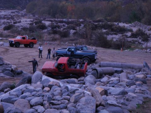 1978 Ford Bronco - Several trucks are gathered in a rocky, outdoor area, possibly for off-roading.