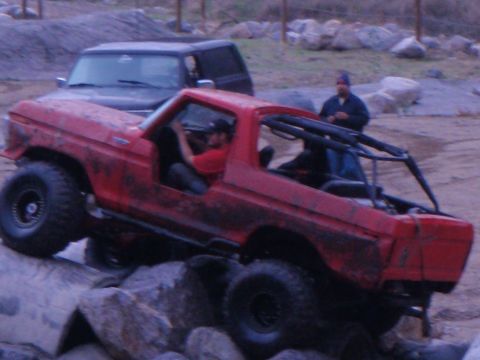 1978 Ford Bronco - A red 1978 Ford Bronco navigates a rocky obstacle course with another SUV in the background.